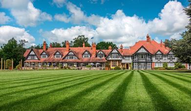 The exterior of a large hotel with well-trimmed lawn.